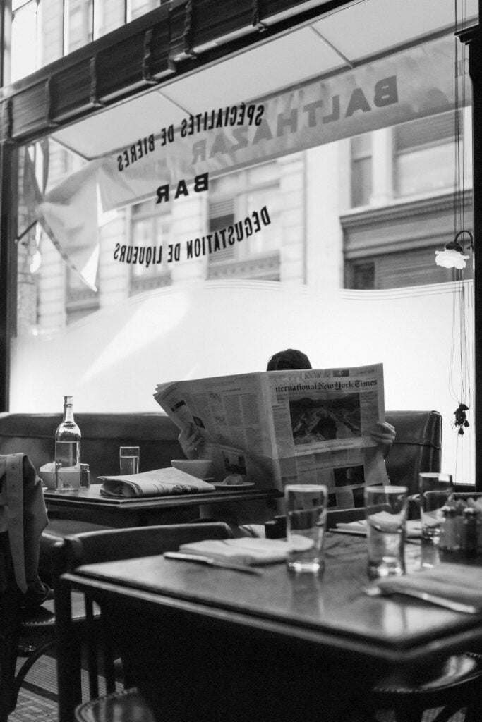 En man sitter i en restaurang och läser en nyhetstidning.
