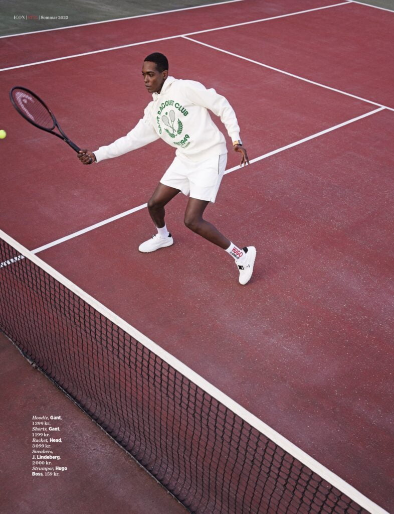 Man i vitt på röd tennisbana